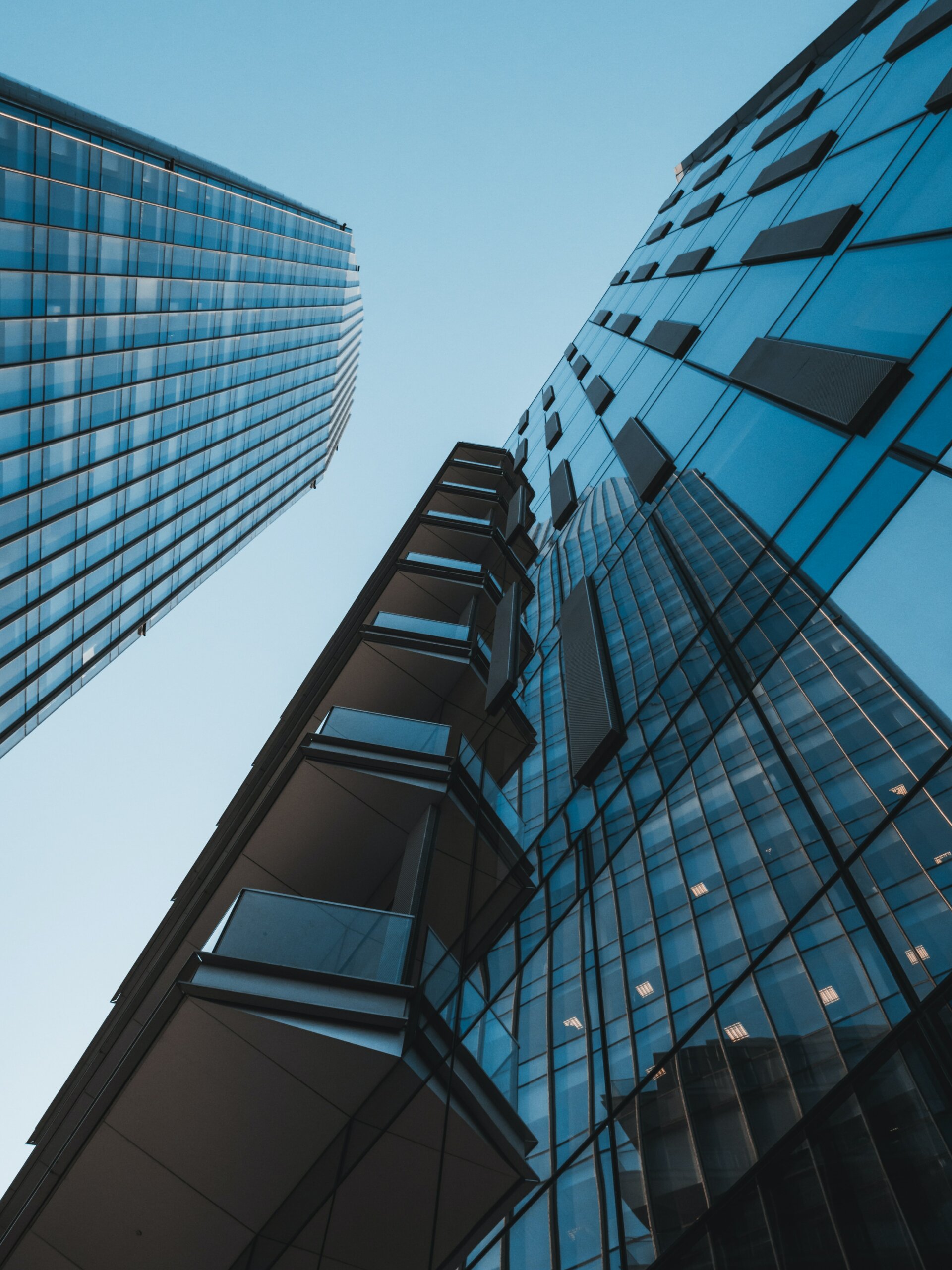 View looking up at two larger glass skyscraper buildings